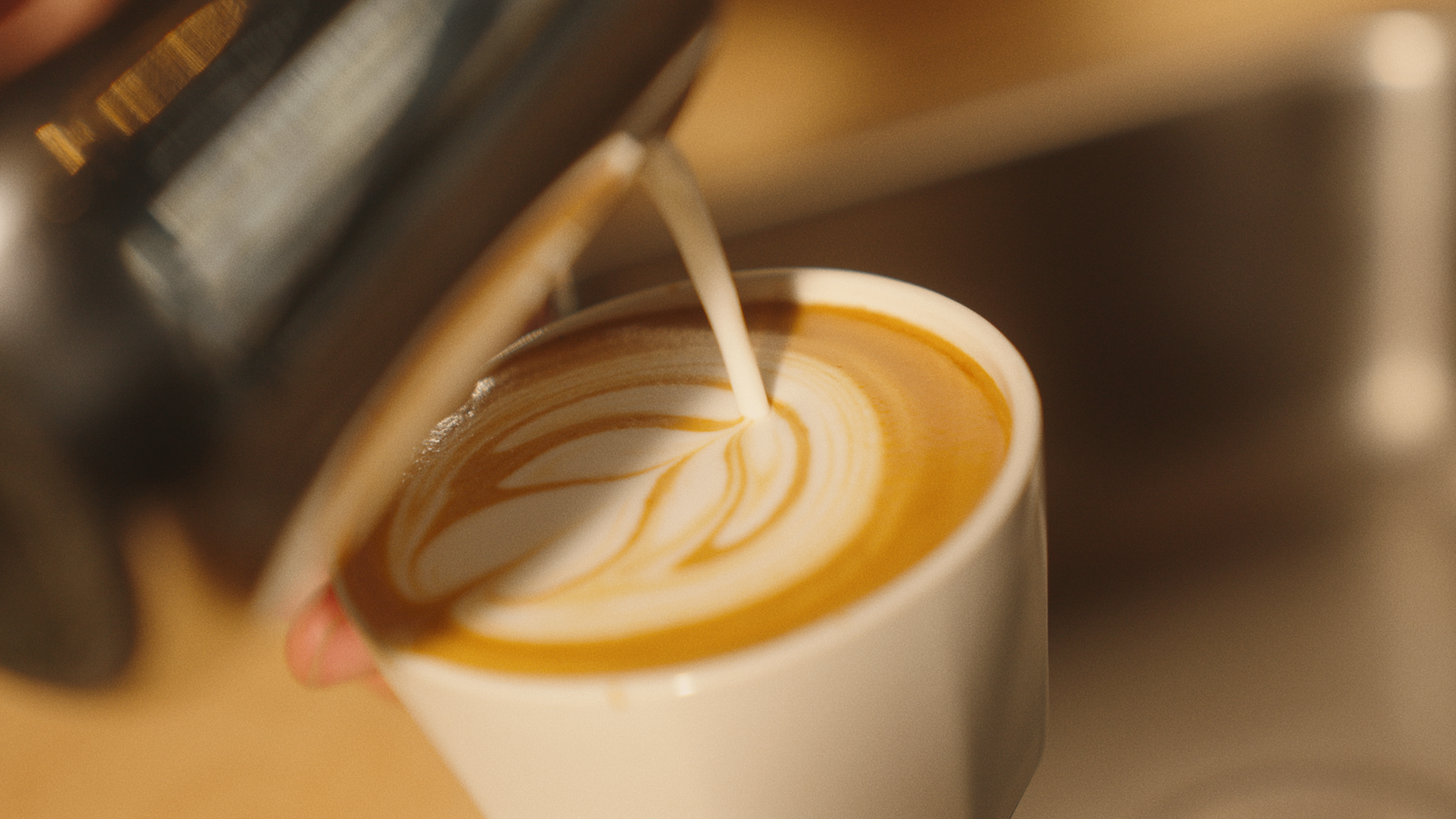 Latte being poured with rosetta art